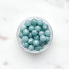 Load image into Gallery viewer, Clear container filled with teal beads on a white background