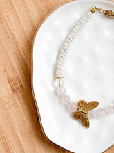 Load image into Gallery viewer, Bracelet with butterfly charm on a white dish with a wooden surface