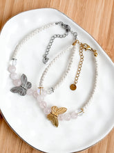 Load image into Gallery viewer, Two butterfly-themed bracelets on a white plate with a wooden background