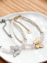 Load image into Gallery viewer, Two butterfly-themed bracelets on a white plate with a wooden surface background.