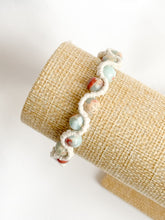 Load image into Gallery viewer, Bracelet with light blue beads on a beige cylindrical stand against a white background
