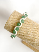 Load image into Gallery viewer, Green beaded bracelet on a beige cylindrical object against a white background