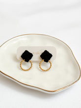 Load image into Gallery viewer, Black earrings with gold loops on a white dish