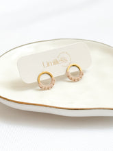 Load image into Gallery viewer, Gold and pink hoop earrings on a white dish with 'Limilless' branding.