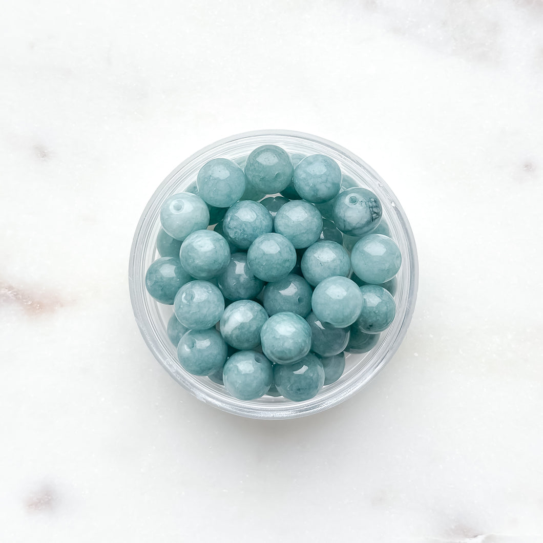 Clear container filled with teal beads on a white background