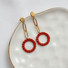 Load image into Gallery viewer, Red circular earrings with gold chains on a white dish
