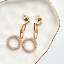 Load image into Gallery viewer, Pair of gold and beige hoop earrings on a white dish.

