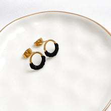 Load image into Gallery viewer, Pair of gold and black hoop earrings on a white plate.
