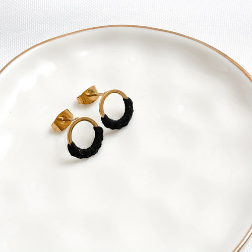 Pair of gold and black hoop earrings on a white plate.