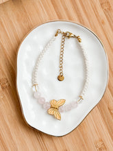 Load image into Gallery viewer, Bracelet with butterfly charm on a white dish on a wooden surface
