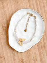 Load image into Gallery viewer, Bracelet with a butterfly pendant on a white dish on a wooden surface
