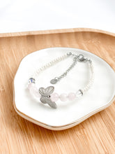 Load image into Gallery viewer, Bracelet with butterfly charm on a white dish on a wooden surface
