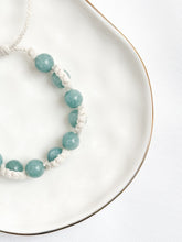 Load image into Gallery viewer, Bracelet with light blue beads on a white plate
