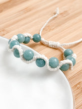 Load image into Gallery viewer, Bracelet with light blue beads on a white plate and wood surface
