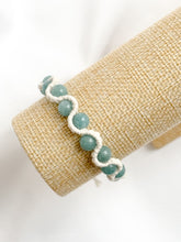 Load image into Gallery viewer, Bracelet with light blue beads on a beige woven surface

