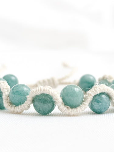 Aquamarine beaded bracelets with white macrame cord on a white background