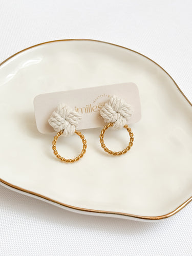 Macrame pair of earrings with gold hoops on a white dish