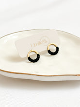 Load image into Gallery viewer, Black and gold hoop earrings on a white dish with &#39;Limiless&#39; branding.
