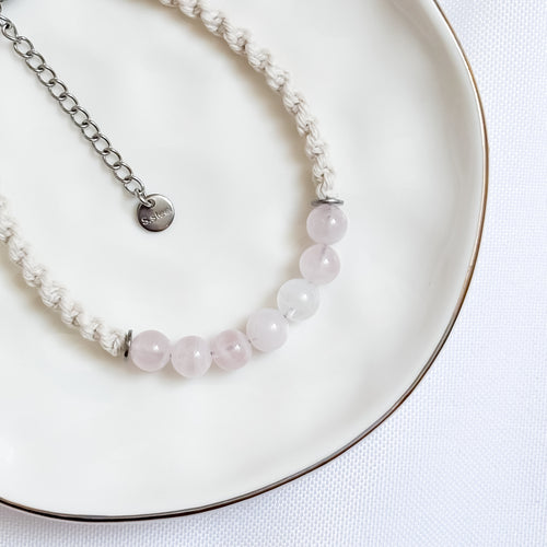 Bracelet with pink beads and silver chain on a white plate