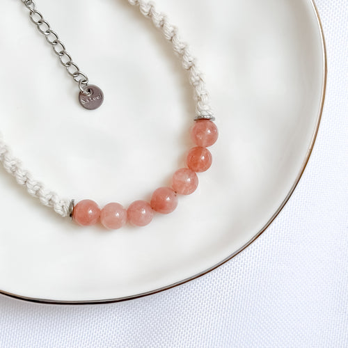 Bracelet with pink beads and silver chain on a white plate
